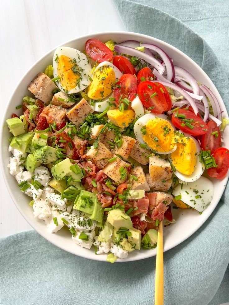 A colorful Cobb Salad with grilled chicken, bacon, avocado, tomatoes, and hard-boiled eggs, topped with a tangy vinaigrette dressing.