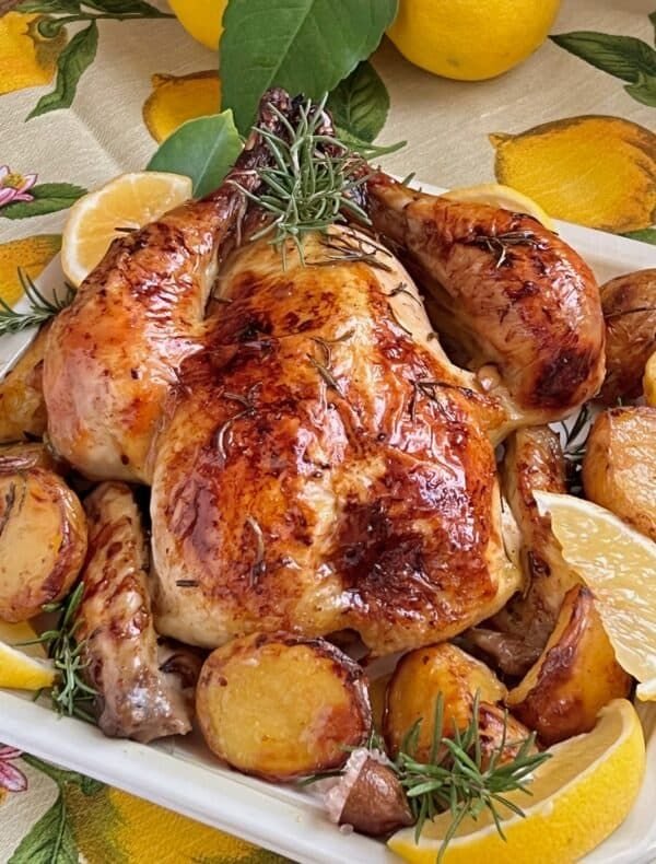 A golden-brown roast chicken served on a platter, with crispy skin and garnished with fresh herbs and lemon wedges, showcasing a perfectly roasted, juicy meal ready to enjoy.